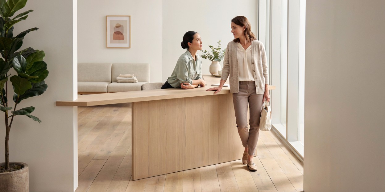 Woman in her forties talking with a receptionist at a clinic front desk